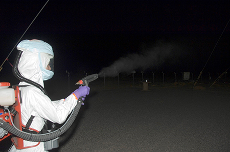 A Special Programs test officer at Dugway Proving Ground,dressed in personal protective equipment, releases a simulant into the air so testing equipment can track its movement and dissemination